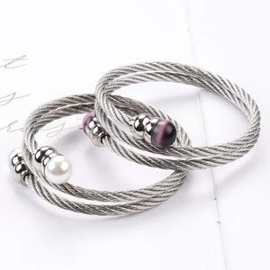 Makroaufnahme von Edelstahl-Kabelarmbändern mit weißer Perle und lila Opal-Perlen für Damen