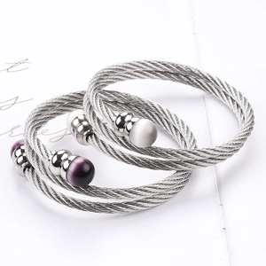 Detailaufnahme gewebter Edelstahl-Kabelarmbänder mit perlenartigen Katzenaugen-Perlen