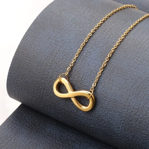 Detailed close-up of a 18k gold infinity symbol pendant on a fine link chain anklet
