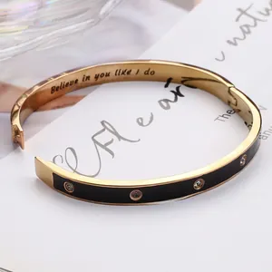 Détail du bracelet doré avec émail noir et gravure intérieure 'Believe in you like I do'