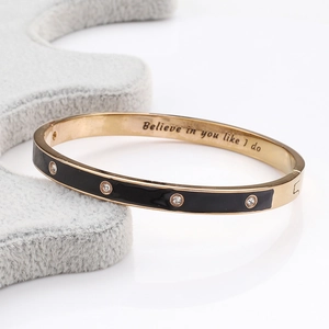 Macro d'un bracelet doré avec émail noir, quatre cristaux et gravure intérieure