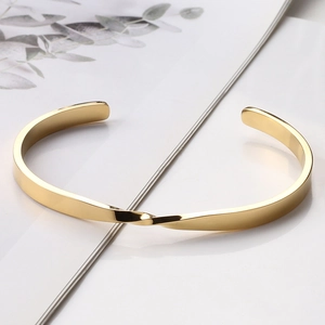 Macro shot of 18k gold Mobius twist bangle with high-polished stainless steel finish