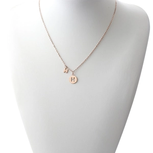 Detail view of rose gold H-letter pendants on a minimalist stainless steel chain