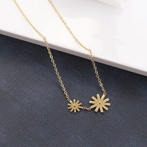 Detail of gold daisy pendants on a delicate cable chain against a leather background