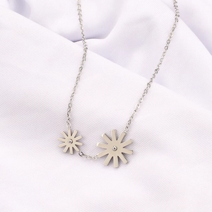 Detailed view of silver stainless steel necklace with two daisy flower starburst pendants