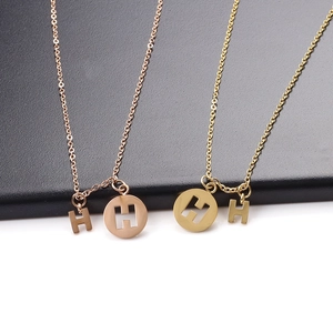 Detail of H-letter pendant necklaces in polished rose gold and yellow gold finishes