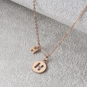Macro view of rose gold letter H and hollow round sunburst pendant necklace