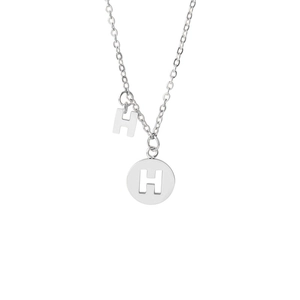 Macro shot of silver stainless steel necklace with double H letter pendants on white background
