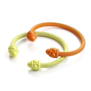 Close-up of dual-tone cable twist bangles in vibrant green and orange enamel finish