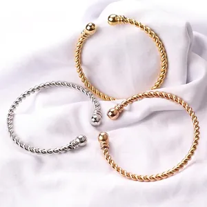 Twisted wire cuff bracelets in gold silver and rose gold on white satin fabric