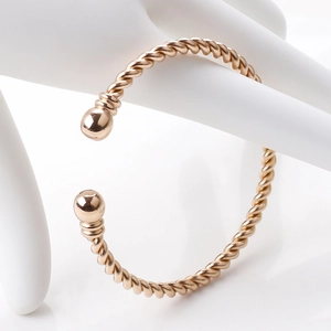 Detail showing rose gold twisted cable cuff bracelet with smooth spherical end caps