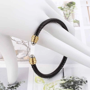 Close-up of black cable wire bracelet with two-tone gold and silver ribbed end caps