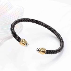 Detail of black twisted steel cable bracelet with gold accents and silver ball ends