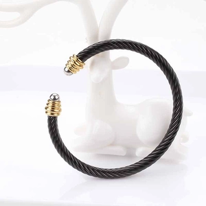 Detail of black twisted cable cuff bracelet with gold and silver tone end caps