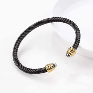Detail of black twisted cable cuff bracelet featuring gold and silver end beads