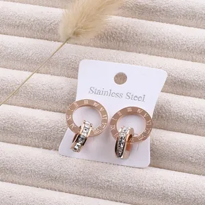 Close-up of rose gold stainless steel earrings with Roman numerals and inlaid crystals