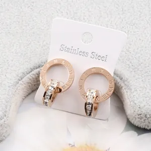 Detail of rose gold stainless steel earrings with Roman numerals and crystals