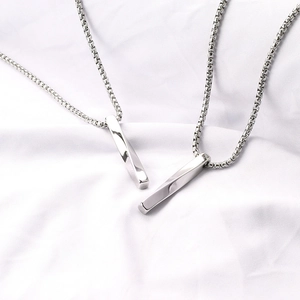 Primo piano di collane con ciondolo Mobius in argento e catene box su un tessuto bianco