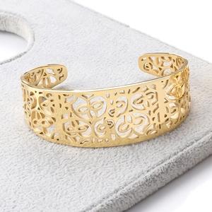 Detailed close-up of gold stainless steel open bangle with hollow floral patterns