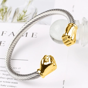 Macro shot of silver cable twisted bracelet with polished gold fist terminal ends
