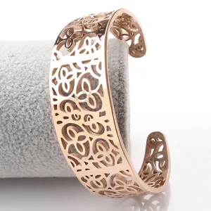 Detailed view of rose gold hollow wide cuff bracelet with floral patterns on velvet stand