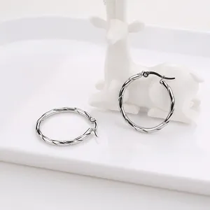 Detailed macro view of silver twisted rope hoop earrings on a decorative white porcelain stand