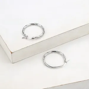 Detailed view of silver twisted wire hoop earrings in stainless steel on white pedestal