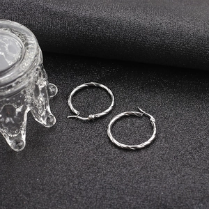 Macro detail of silver twisted rope textured hoop earrings on a black background