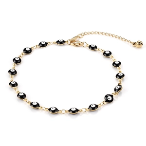 Dettaglio del bracciale malocchio con catena dorata, perle in smalto nero e campanello