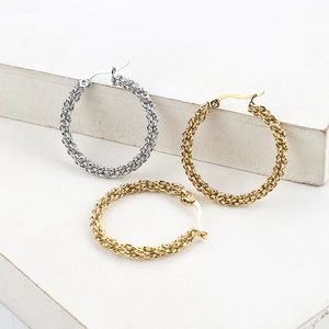 Elegant 18k gold and silver braided hoop earrings displayed on white stone pedestals