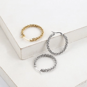 Detailed view of gold and silver twisted cable hoop earrings on a stone display