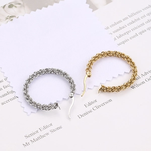 Macro detail of 18k gold and silver woven textured hoop earrings on minimalist background