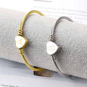 Détail de bracelets torsadés en forme de cœur avec gravures des initiales A et B