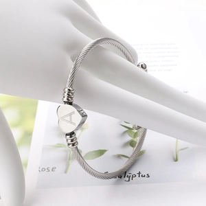 Détail du bracelet en câble d'acier argenté avec pendentif cœur et lettre A gravée