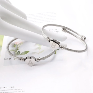 Détail de bracelets cœur en câble argenté avec lettres gravées A et B sur un mannequin