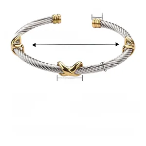 Detail view of two-tone cable cuff bracelet featuring gold X charms and silver stainless steel