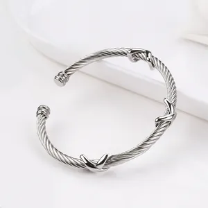 Macro detail of silver twisted cable bangle featuring three polished X-shaped cross charms