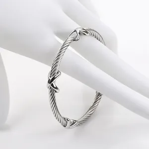 Detailed close-up of a silver cable twist bracelet with triple X-shaped knot accents
