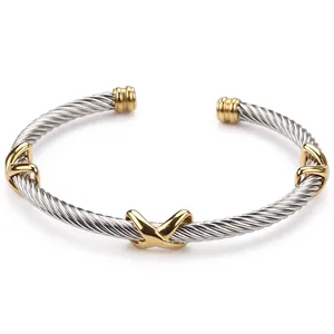 Detail of two-tone twisted cable bangle with gold X motifs and open C-shape design