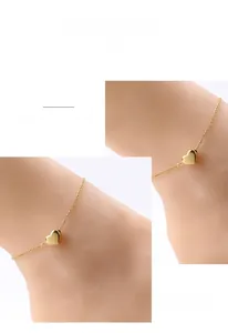 Close-up of a minimalist gold heart pendant on a delicate O-chain anklet for women