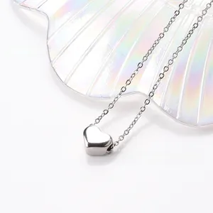 Macro view of polished silver heart pendant necklace on an iridescent shell tray