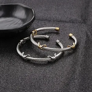Gold and silver twisted cable bracelets with X motif crossover symbols on black background