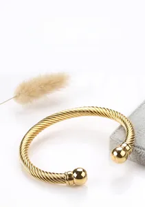 Detailed close-up of a gold cable twisted bangle with ball ends and sleek metallic texture