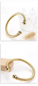 Macro detail of golden stainless steel cable twisted bracelet with spherical end caps