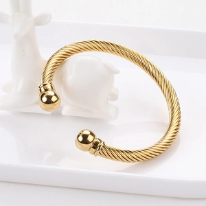 Detail of twisted cable gold bracelet featuring polished sphere end caps on white tray