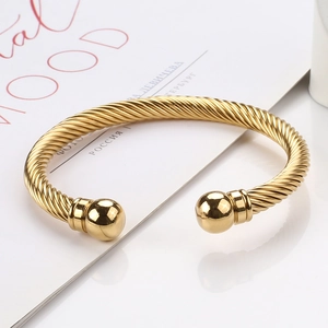 Macro shot of gold twisted cable cuff bangle with polished ball ends on a fashion magazine