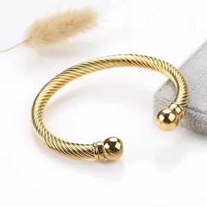 Detail of a gold twisted cable cuff bracelet with polished ball ends on a jewelry pad