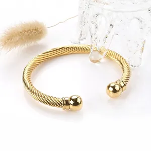 Detail of golden twisted cable stainless steel bangle with polished ball ends for women
