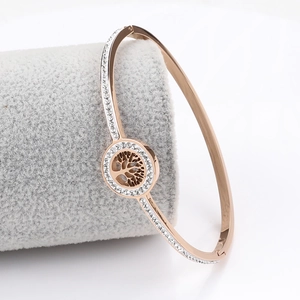Detailed view of Tree of Life rose gold bangle with pave diamonds on a velvet stand
