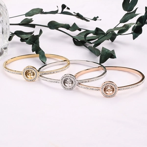 Detailed view of polished Tree of Life bangles in gold, silver, and rose gold finish